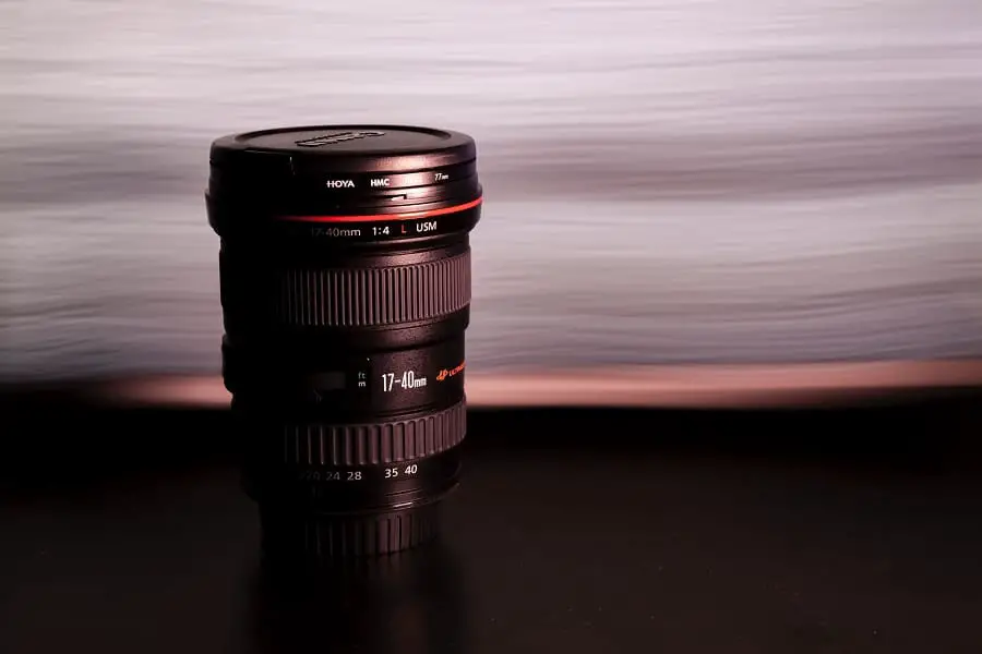 A Canon lens placed on a black surface