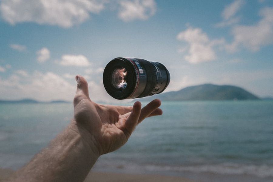 Hand holding a Canon lens that is perfect for shooting landscape images