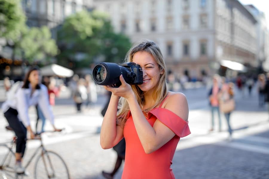 Woman taking photos of a busy street using a Canon camera