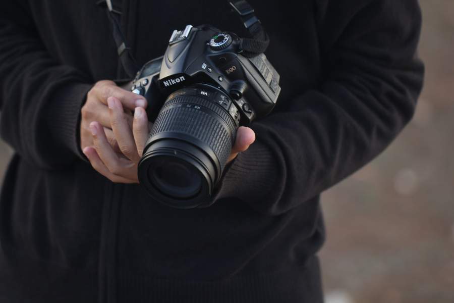 A photographer carrying a Nikon camera with sports photography lens