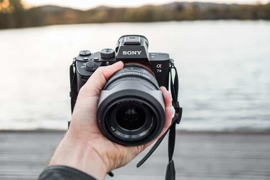 A photographer holding a camera with Sony lens