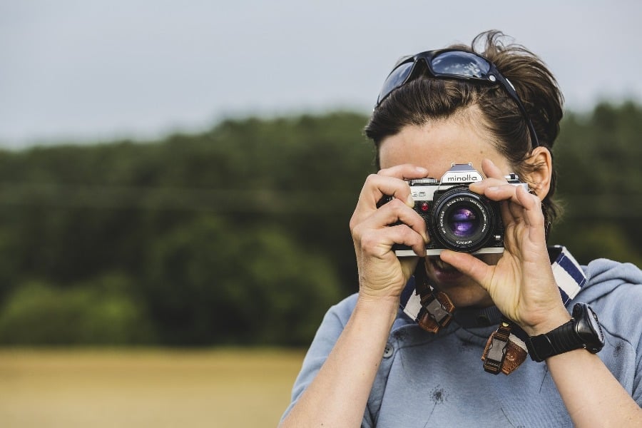 Woman adjusting her camera lens while trying to take a photo
