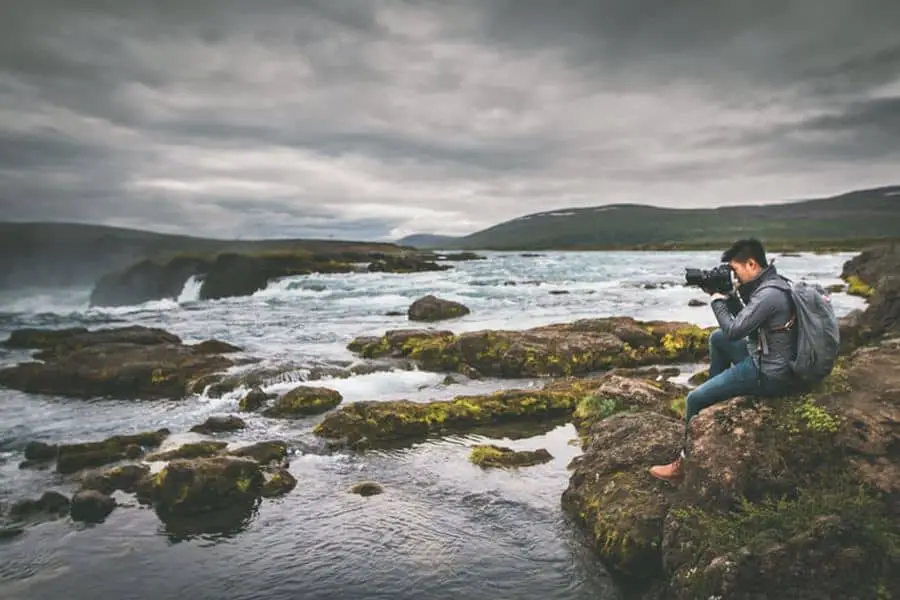 Man taking a wide angle photo of a rocky sea