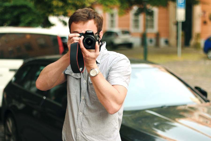 Man taking a photo beside a car